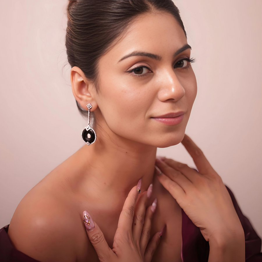 A woman in a black dress and earrings, exuding elegance and style.