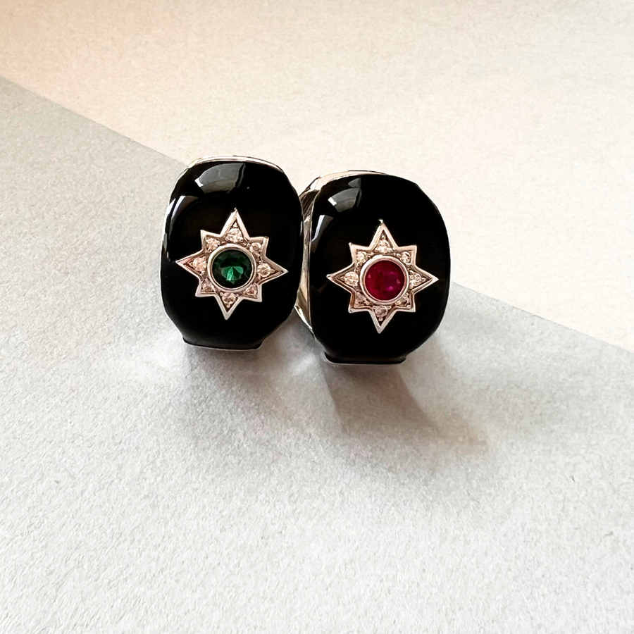 Two black onyx earrings with emerald and diamond star-shaped accents. Elegant and sophisticated jewelry.