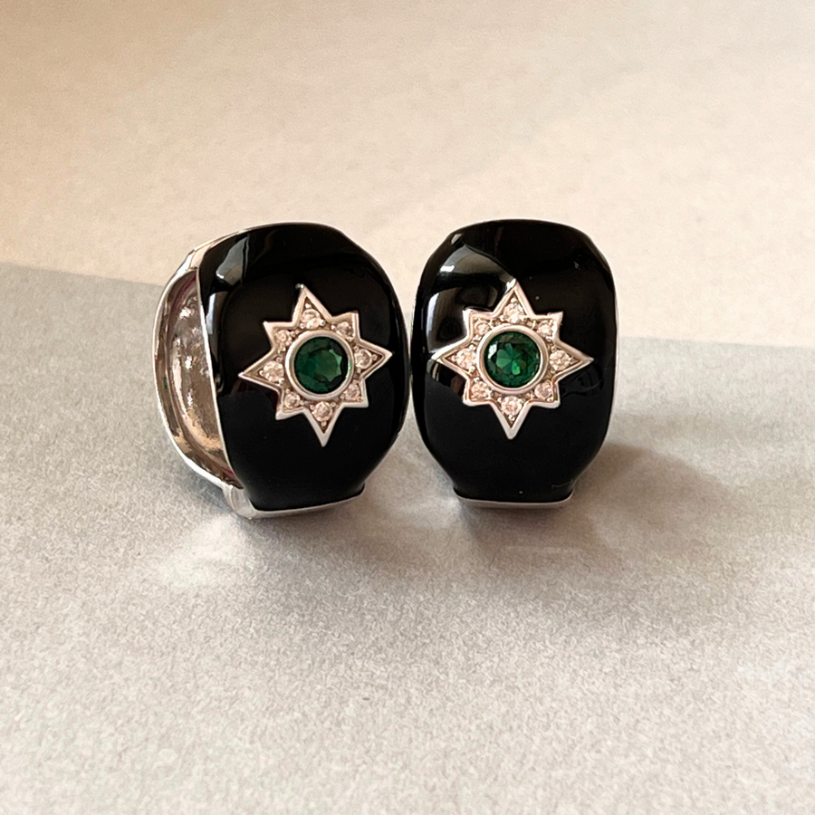 A pair of elegant black onyx earrings adorned with shimmering emerald stones, exuding timeless beauty.