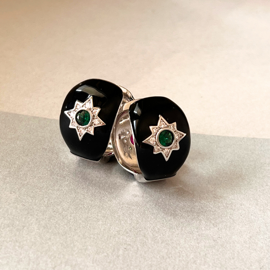 A pair of black and white star earrings with emeralds, adding a touch of elegance and sparkle to any outfit.