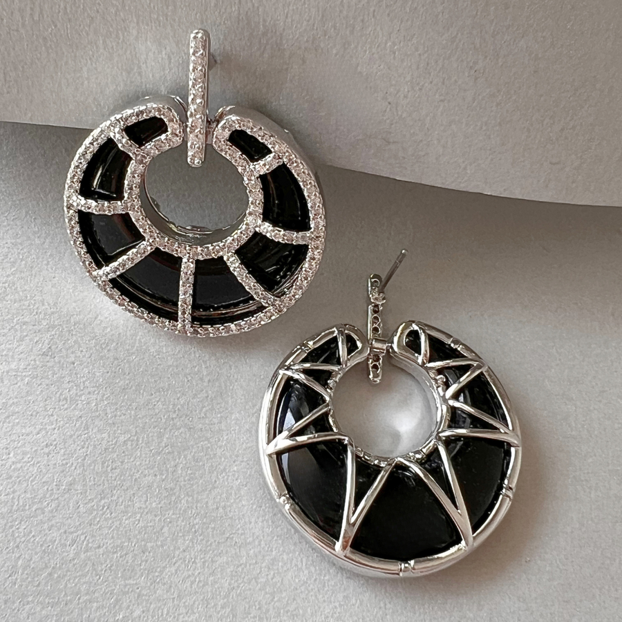 Two elegant black and white earrings adorned with sparkling diamonds, perfect for adding a touch of sophistication to any outfit.