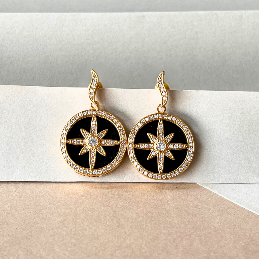 Black and gold star earrings on a white background, adding a touch of elegance and sophistication.
