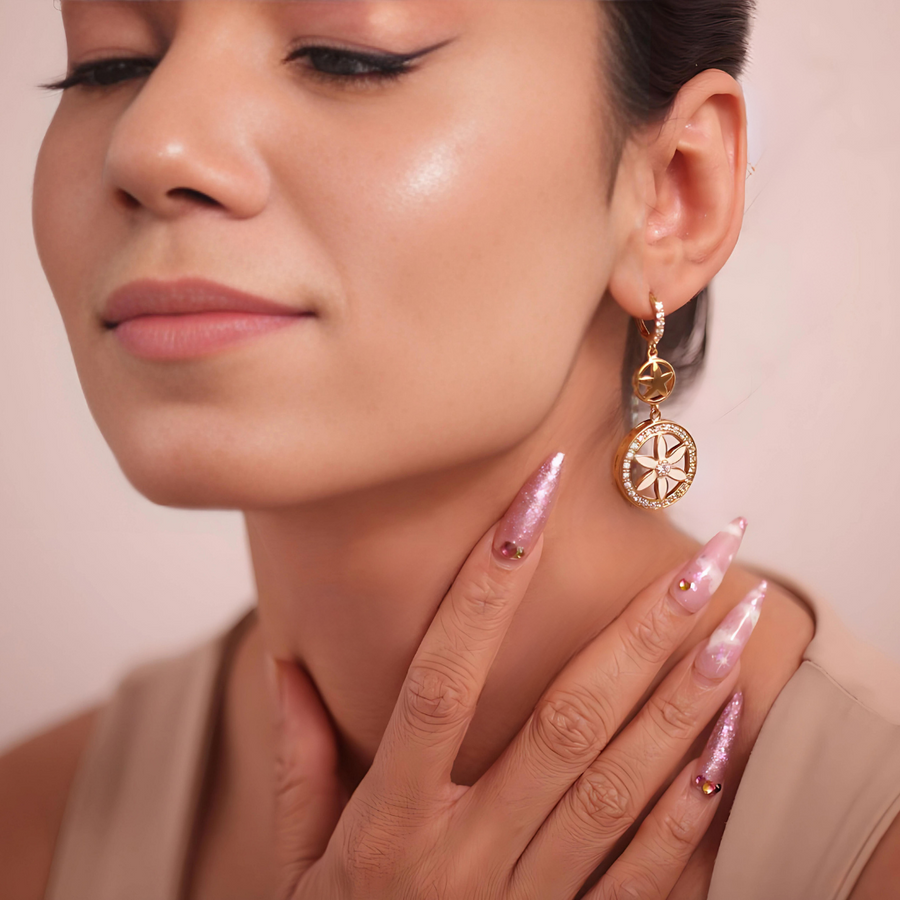 A woman with pink nails and gold earrings, radiating elegance and style.