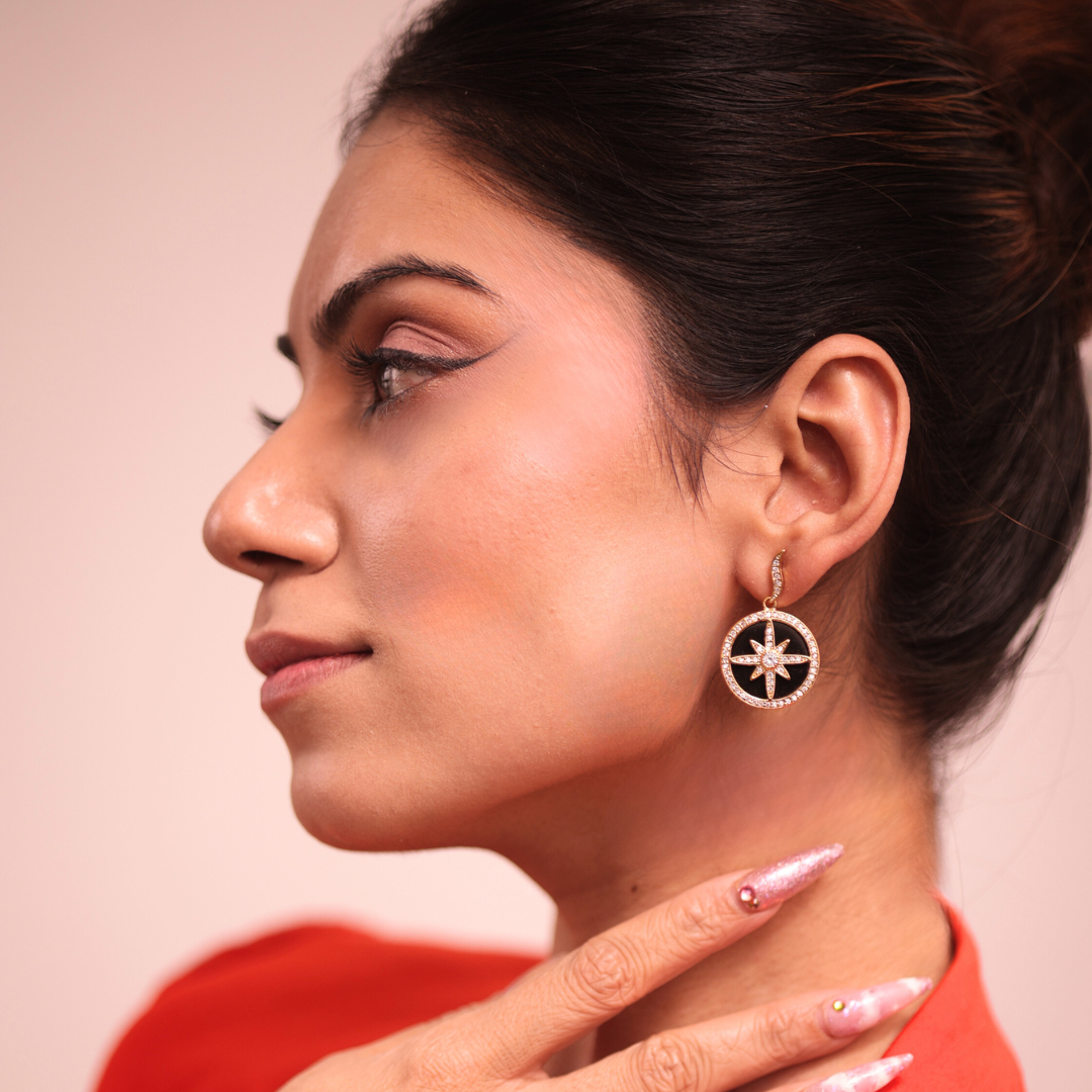 A woman in a red shirt and black earrings.