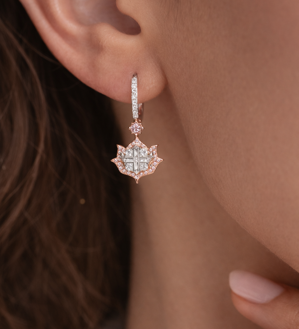 Close-up of a person wearing a rose gold earring with a diamond-like center.