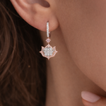 Close-up of a person wearing a rose gold earring with a diamond-like center.