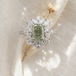 Diamond ring with a green gemstone on a soft fabric background