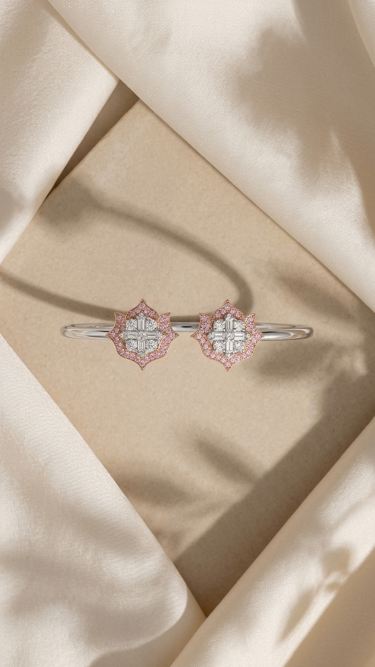 A pair of silver-toned bangle bracelets with diamond-like floral clusters accented by pink stones, displayed on a beige textured surface surrounded by draped cream satin fabric.